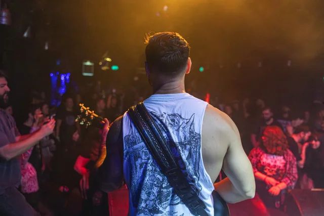 A view from behind a Mental Maze guitarist facing the audience