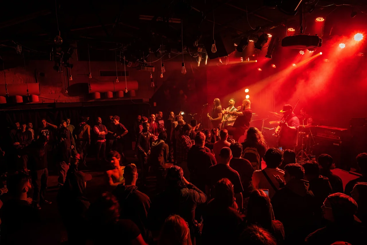 A packed audience in front of Mental Maze under crimson stage lights
