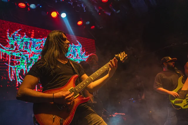 A Mental Maze guitarist performing under red lights