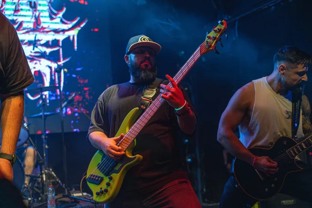Mental Maze's bassist performing with a bright green bass